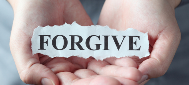 Torn piece of paper with the word "Forgive" in the woman's palms.